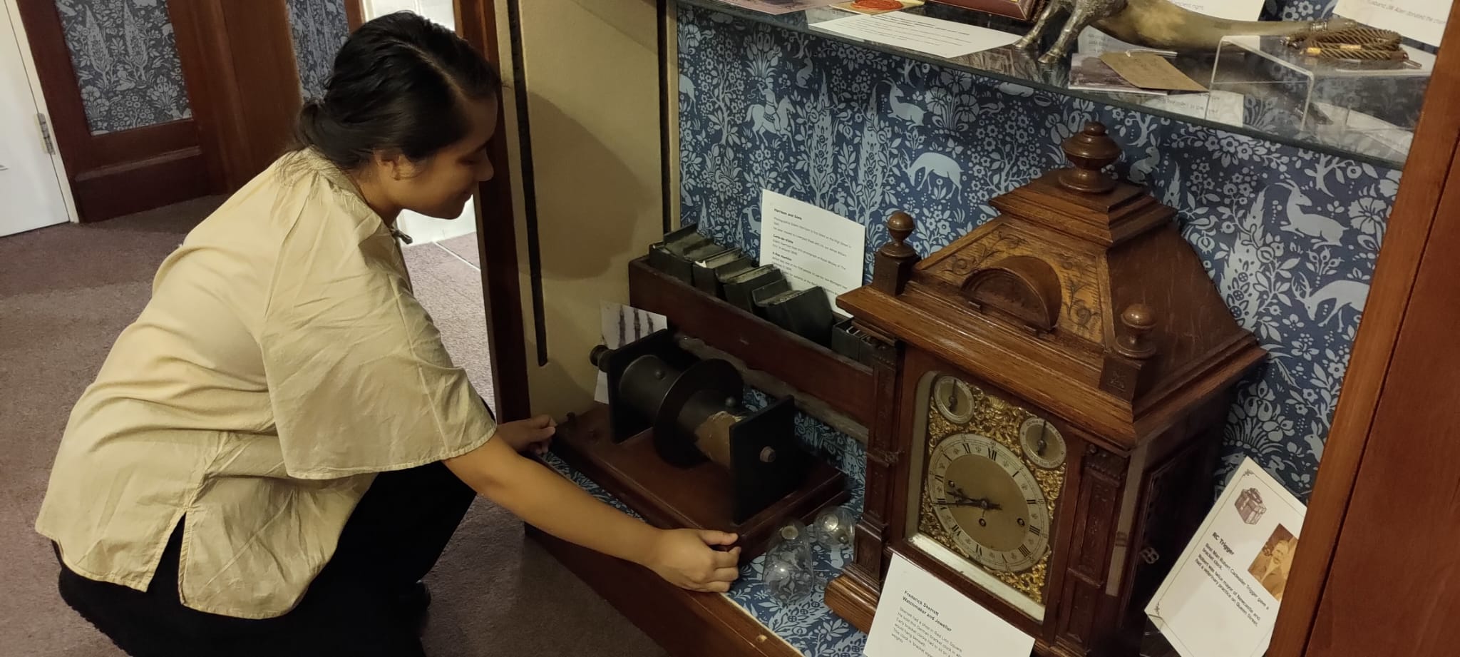 Bethany crouches down to place a part of the X-Ray Machine into a low display case.