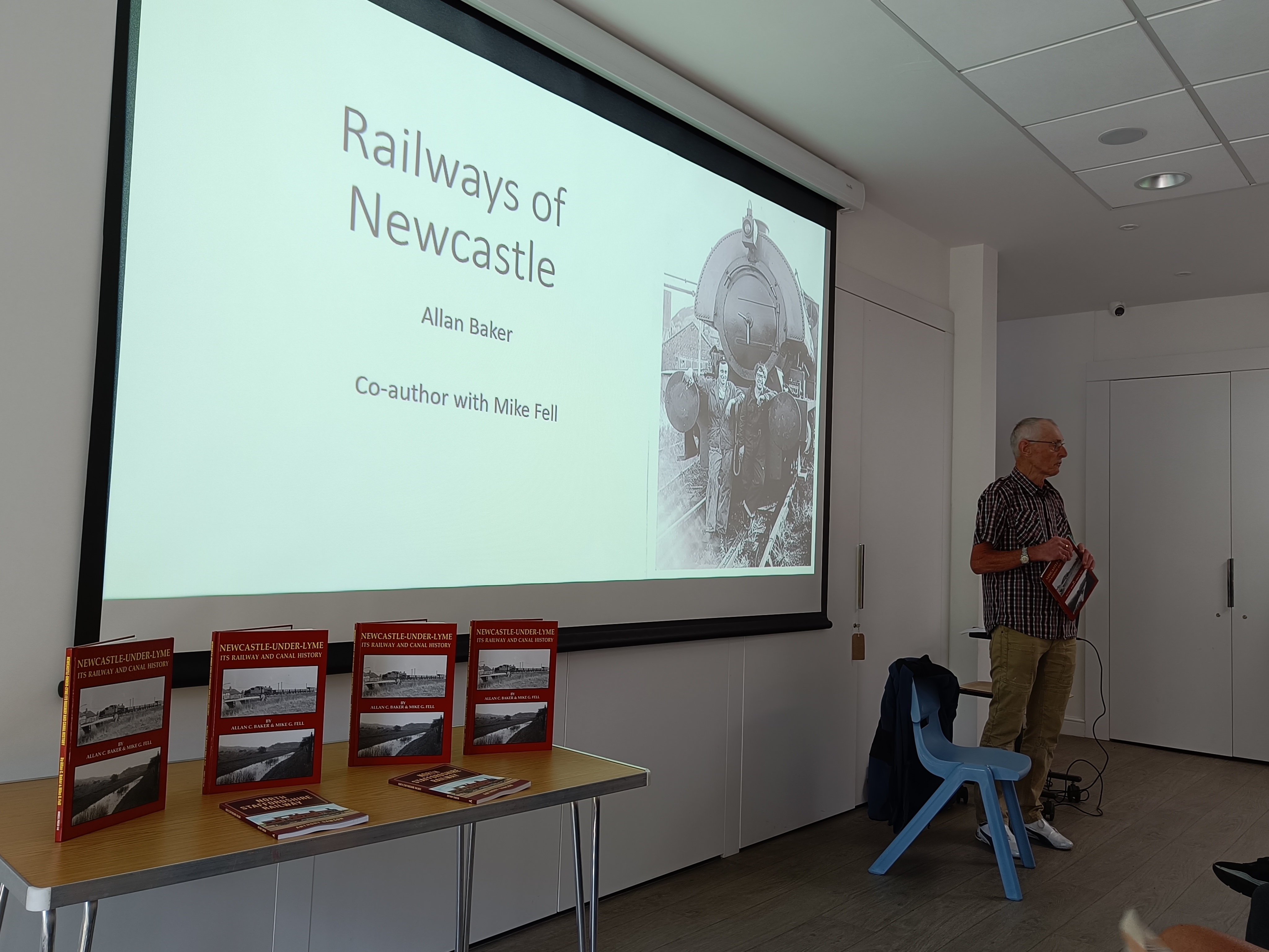 An author stands in front of the large screen