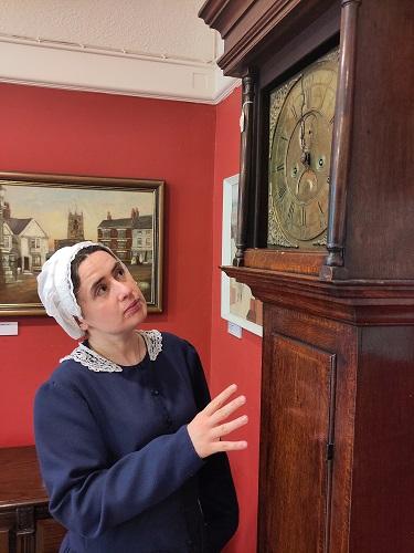 Image of woman standing next to an old clock