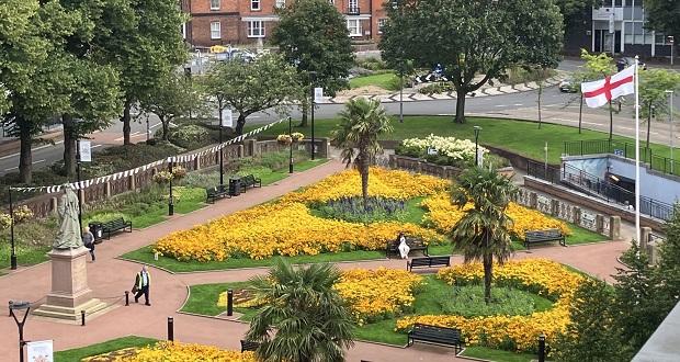 The image shows the flag of St George flying above Queens Gardens.