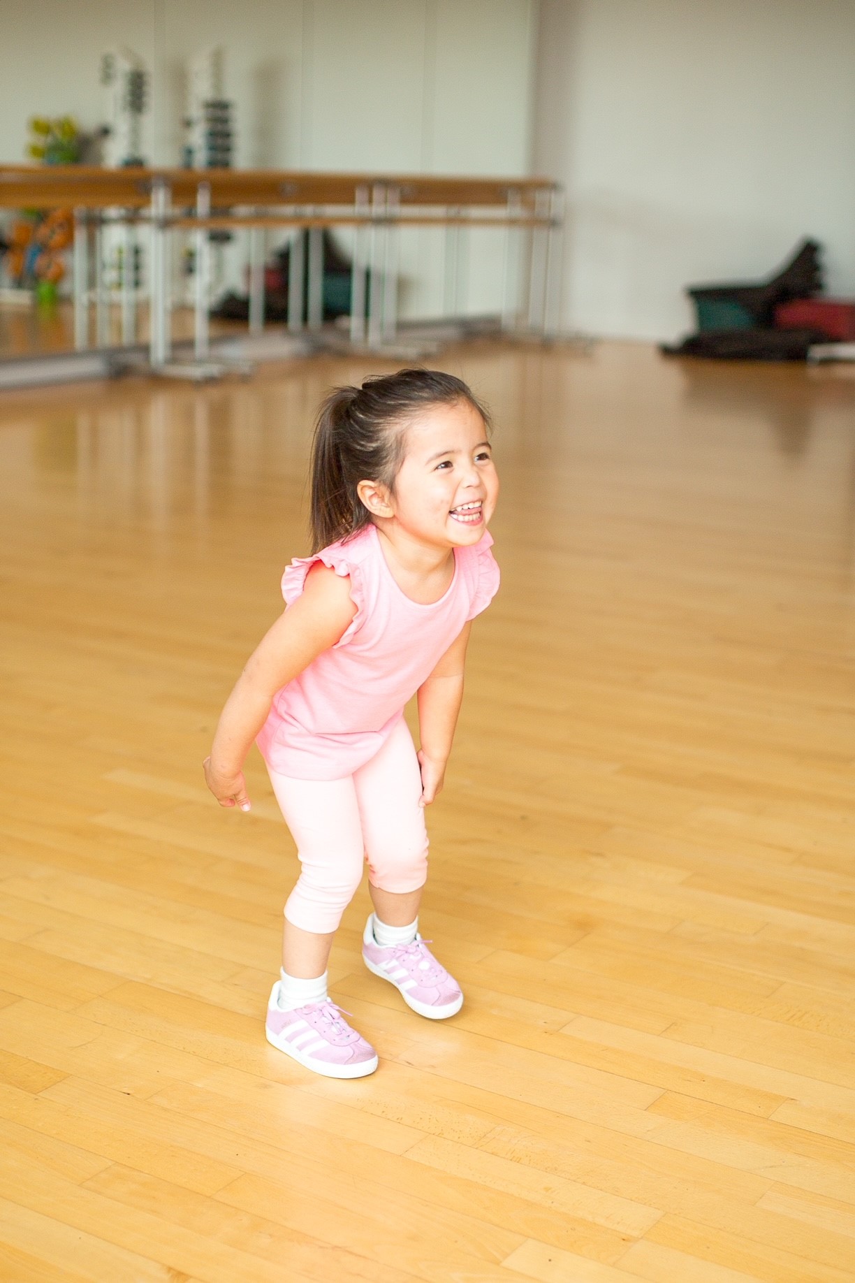 A smiling toddler girl in a dance studio