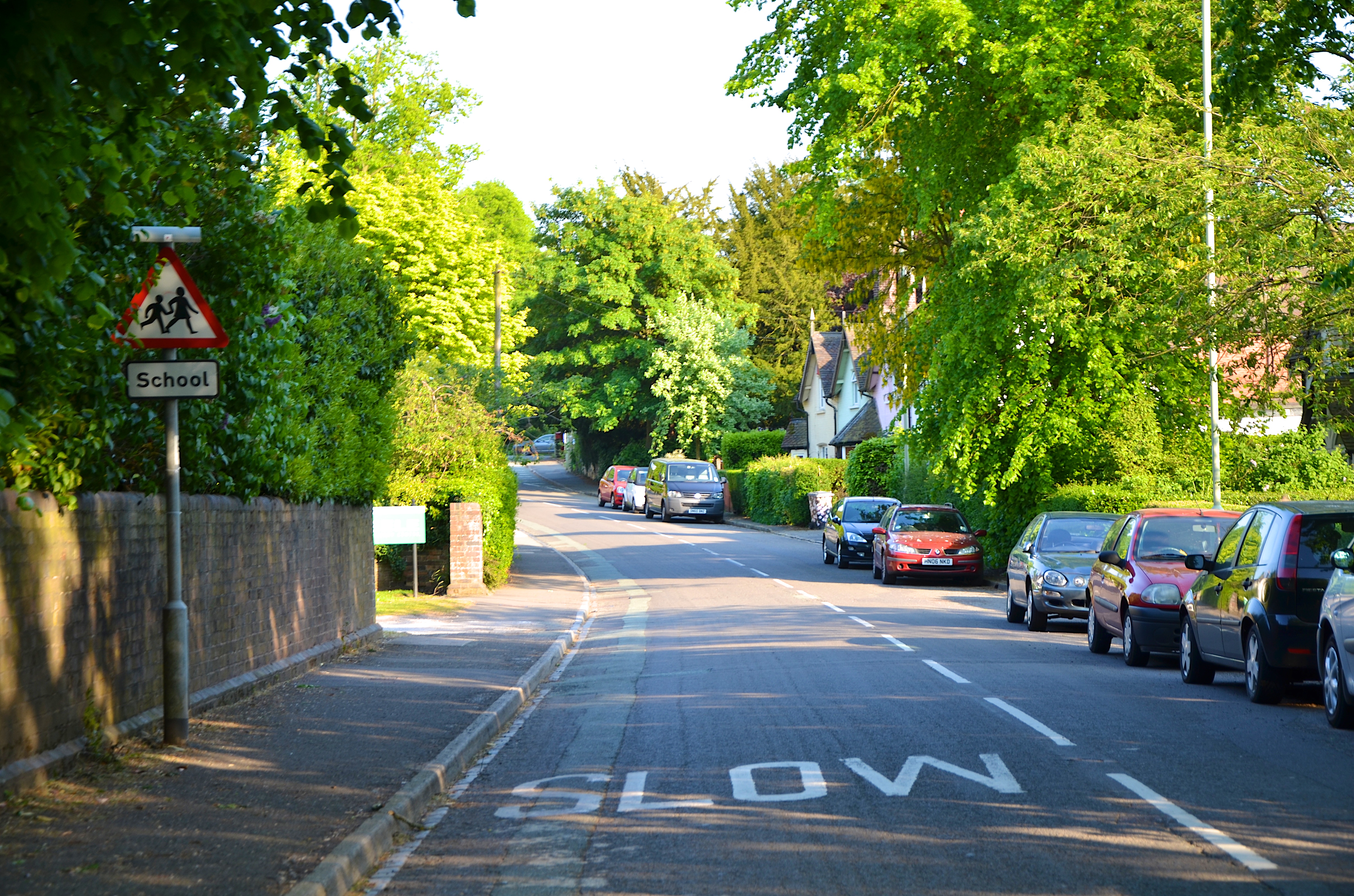 Image of Keele Village, with parked cars on the right-side of the road