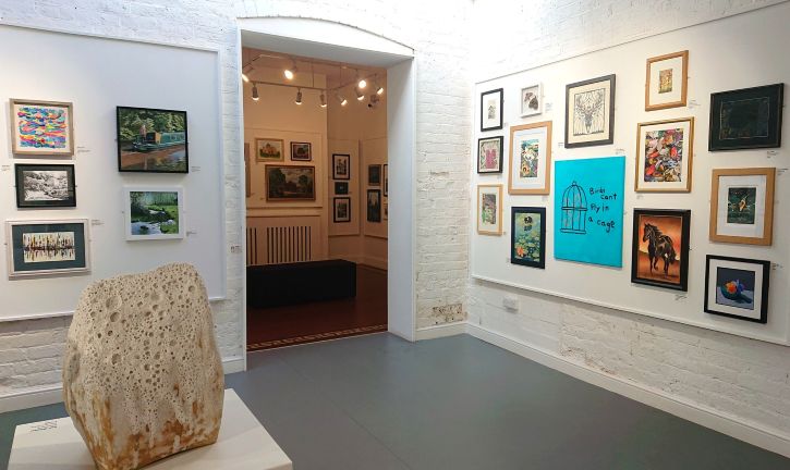 A brightly lit gallery full of paintings and sculptures