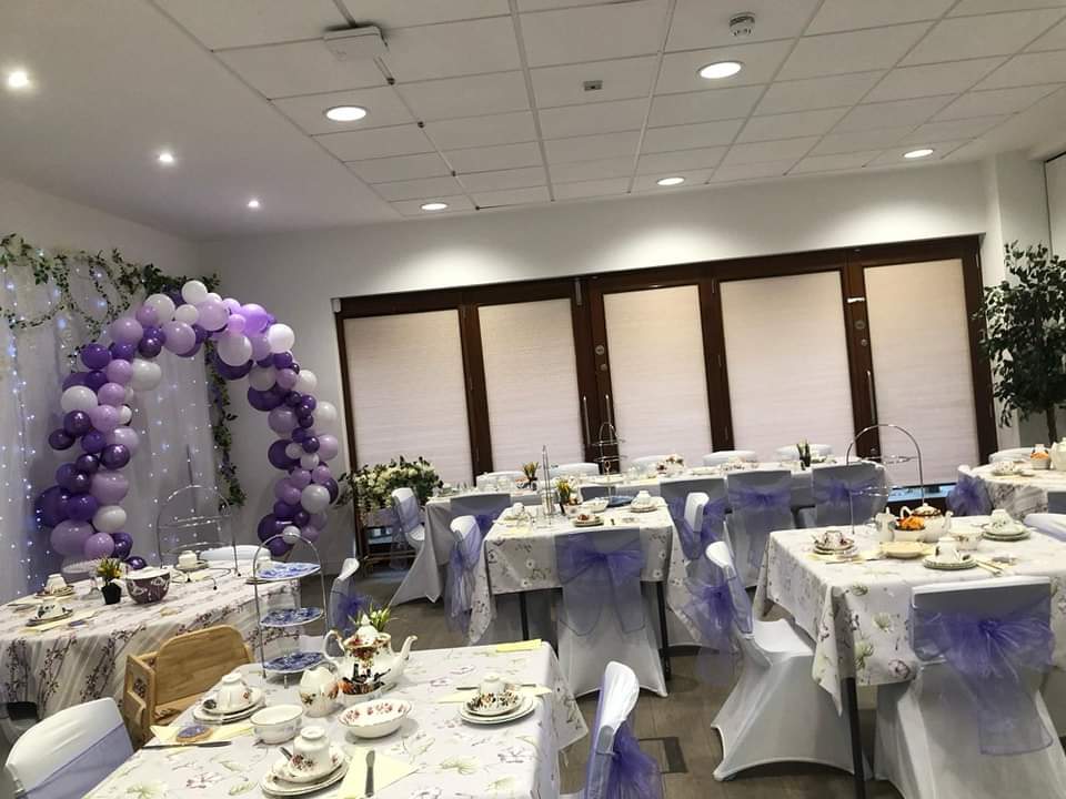 The willow room decorated for an afternoon tea with covered chairs and a balloon arch