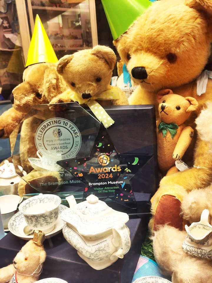A group of historic teddby bears wear party hats and surround an award